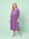 Woman wearing a purple floral dress against a light green background