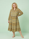 Woman wearing a yellow patterned dress against a light green background